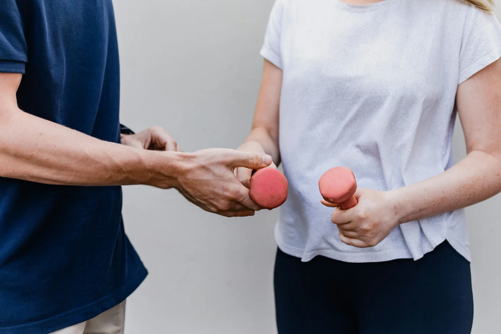 Physiotherapeut übergibt einer Patientin Kurzhanteln für die verordnete Übung. Der Nachweis der ärztlichen Verordnung entscheidet, ob die Heilbehandlung umsatzsteuerfrei bleibt