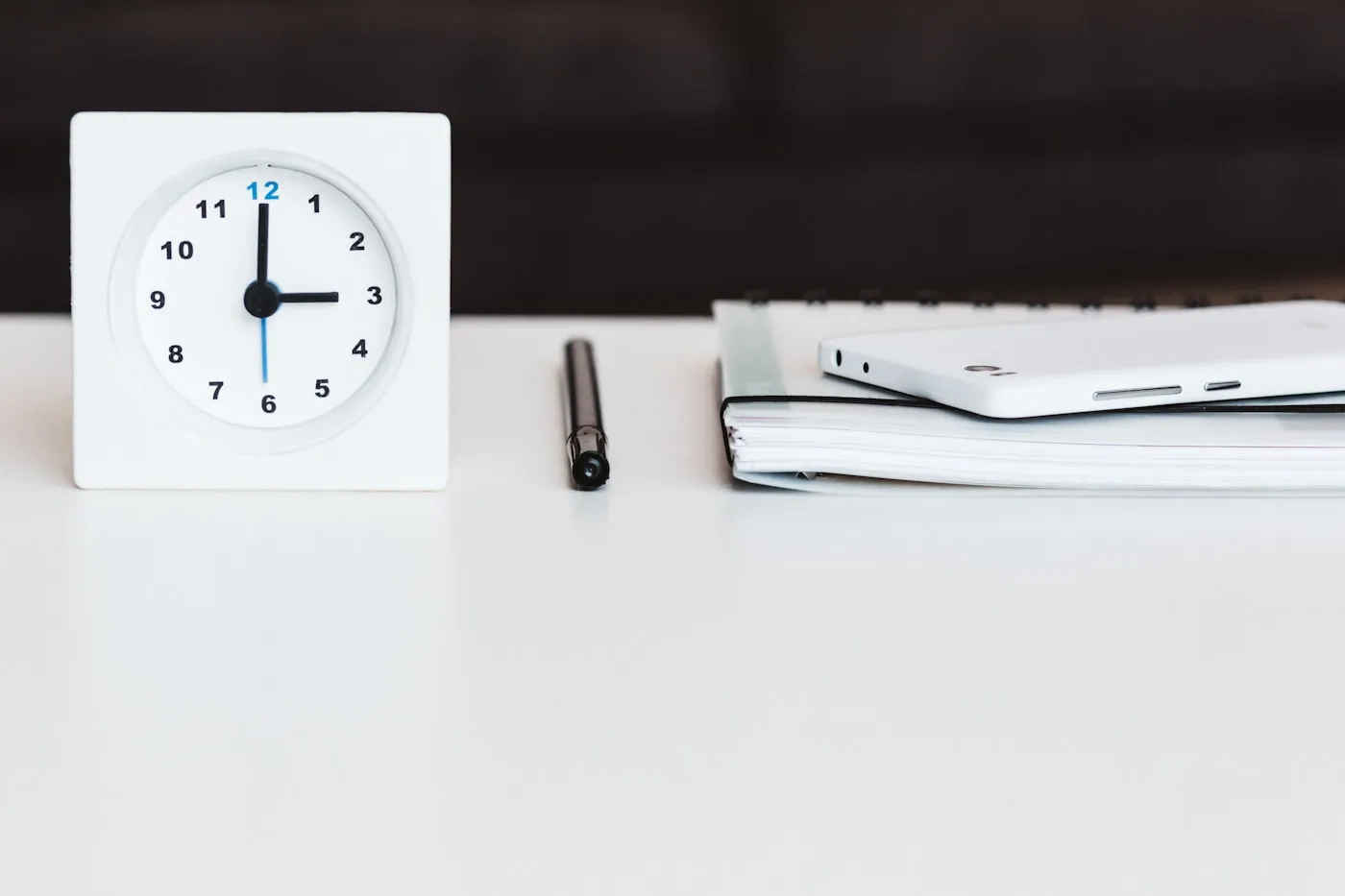 Uhr, Stift und Notizblock auf einem Schreibtisch – UVA-Frist nicht verpassen und Verspätungszuschlag beim Finanzamt vermeiden