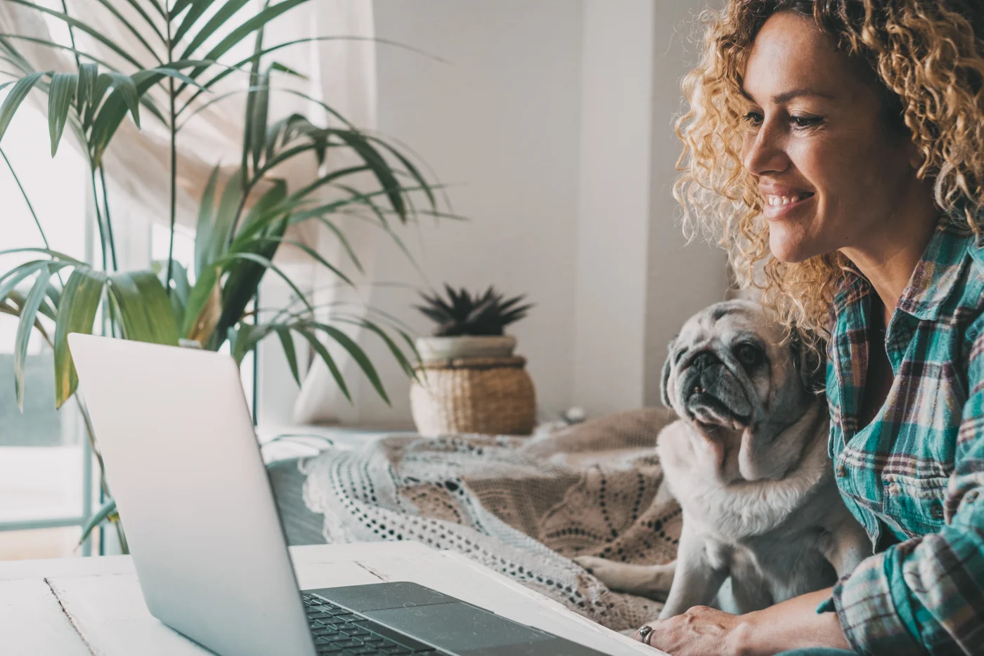 Freelancerin arbeitet mit ihrem Hund an der Seite entspannt am Laptop im Homeoffice