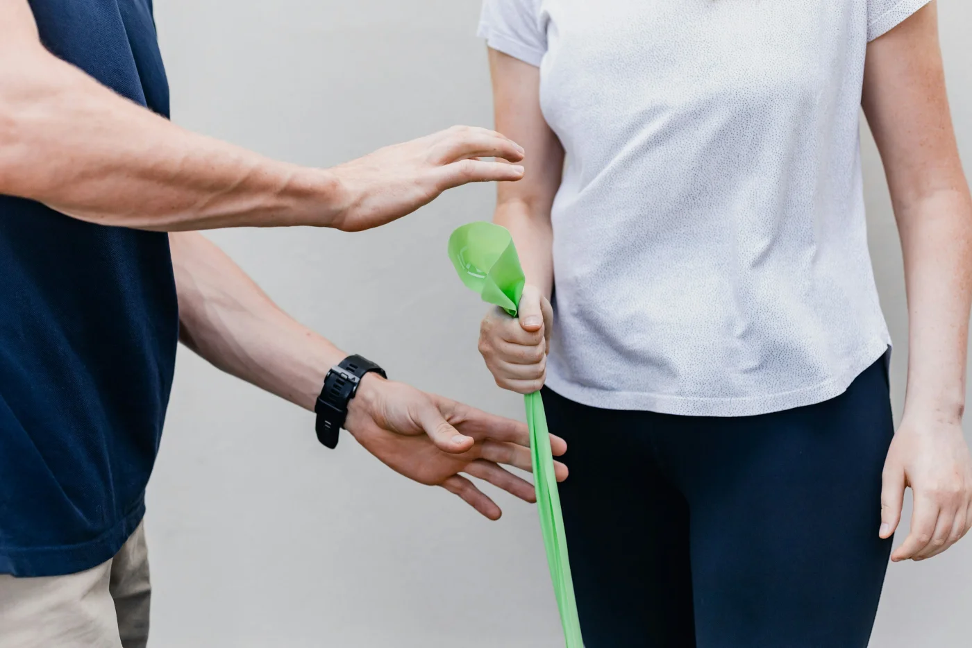 Physiotherapeut leitet eine Patientin bei einer Übung mit dem Theraband an
