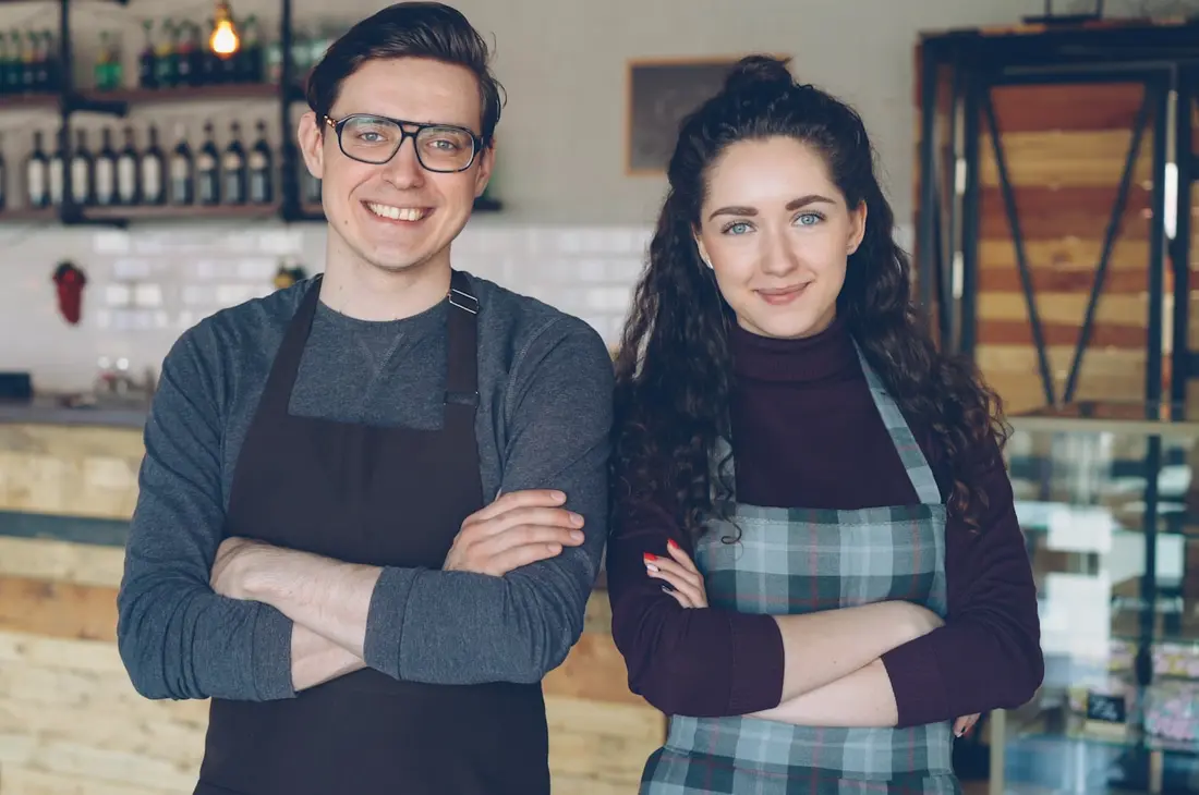 Zwei Café-Betreiber stehen gemeinsam in ihrem Lokal
